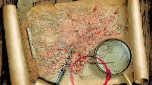 magnifying glass on table with old treasure map scroll and ruler